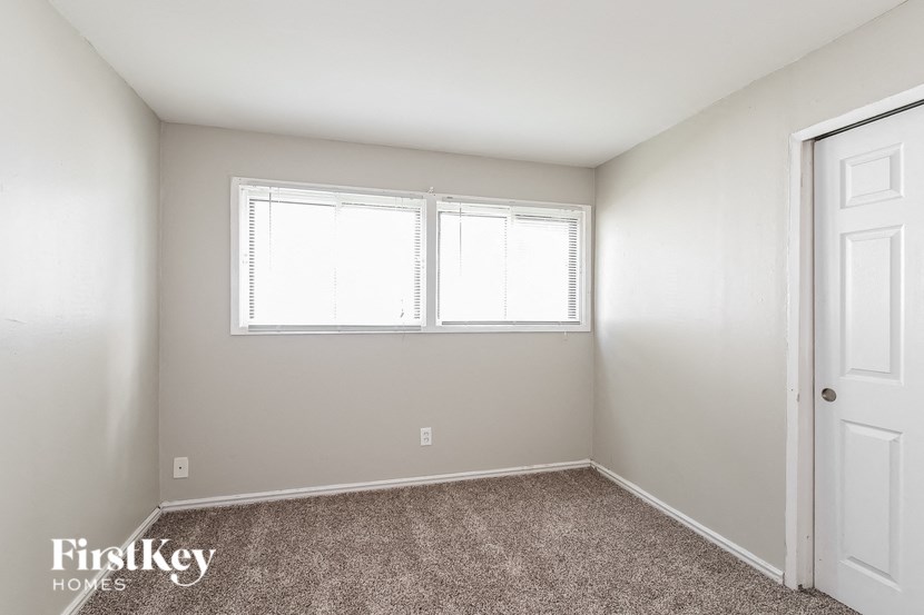 a bedroom with two windows and a carpeted floor