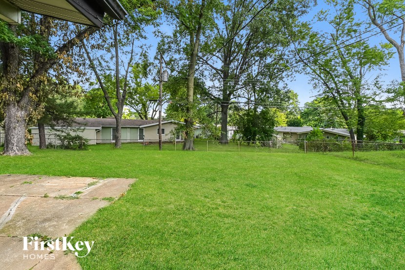 a yard with a house in the background and trees