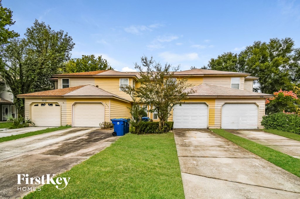a yellow house with white garage doors and a sidewalk