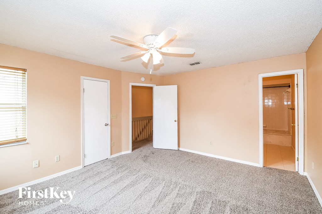 a living room with a carpeted floor and a ceiling fan