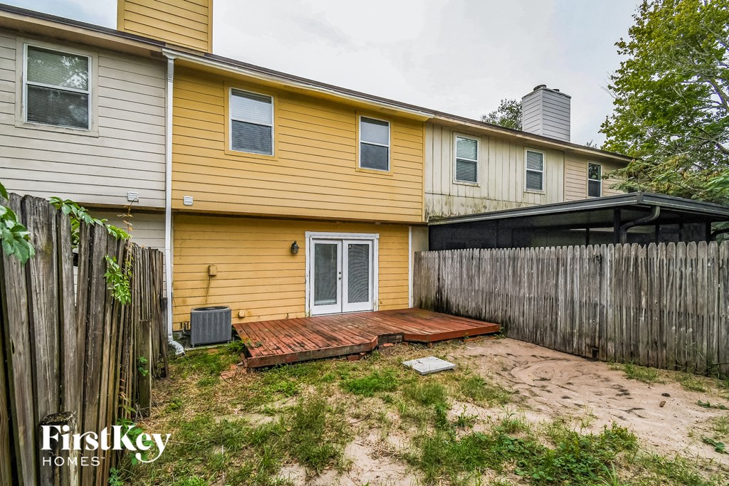 a backyard with a wooden deck and a yellow house