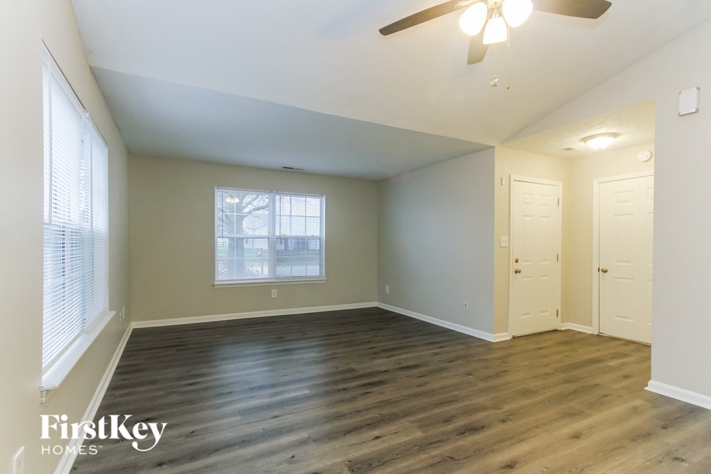 A room with a ceiling fan and wooden flooring.