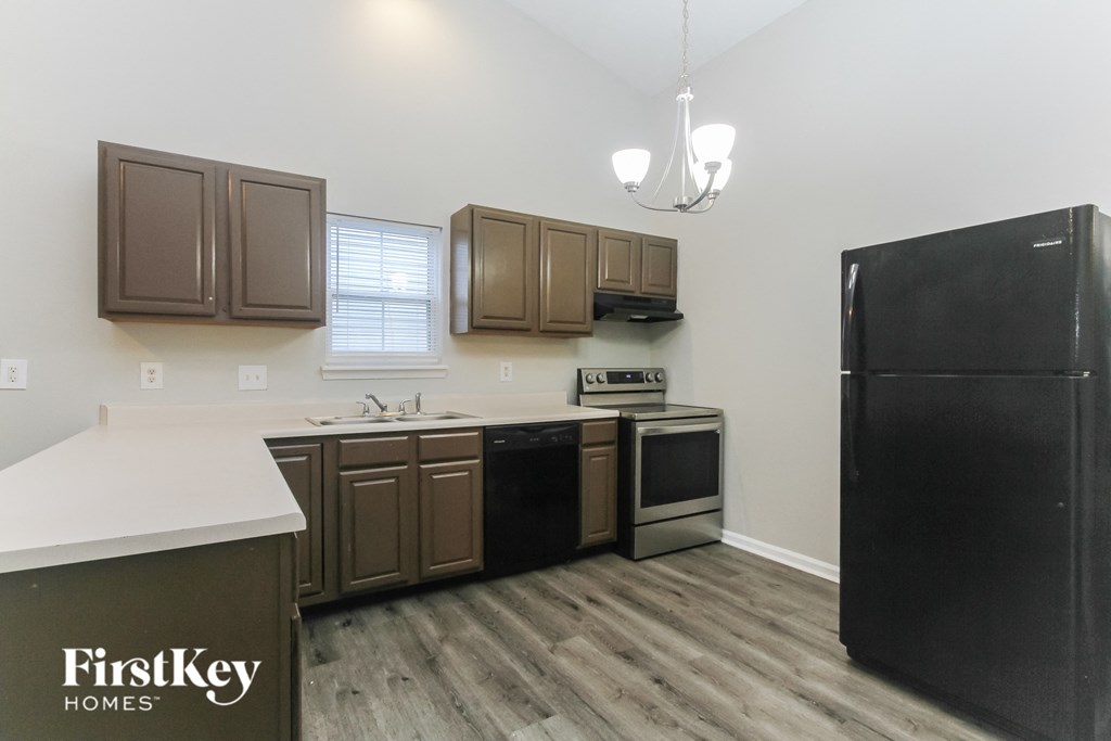 A kitchen with wooden cabinets and a black refrigerator.