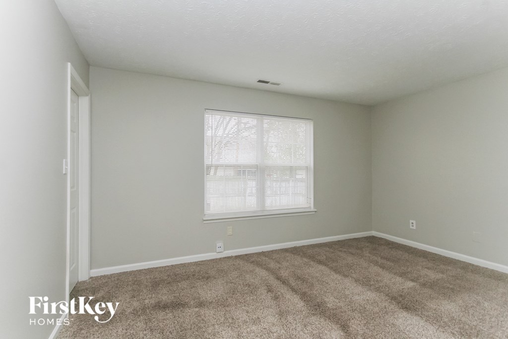 A room with a carpeted floor and a window with blinds.