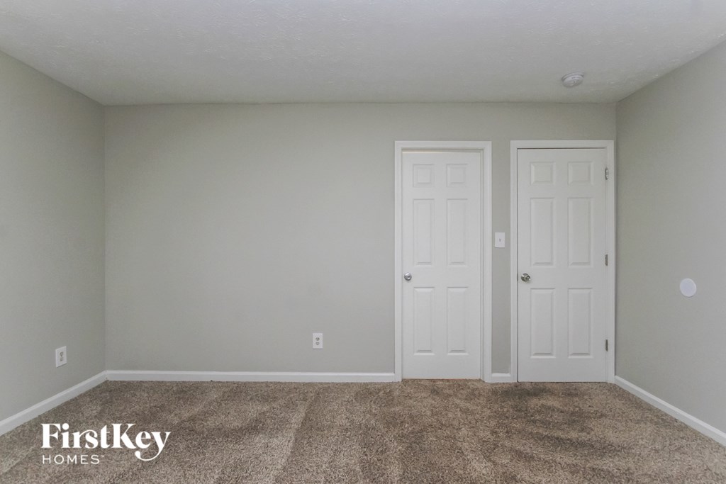 A room with two doors and a carpeted floor.
