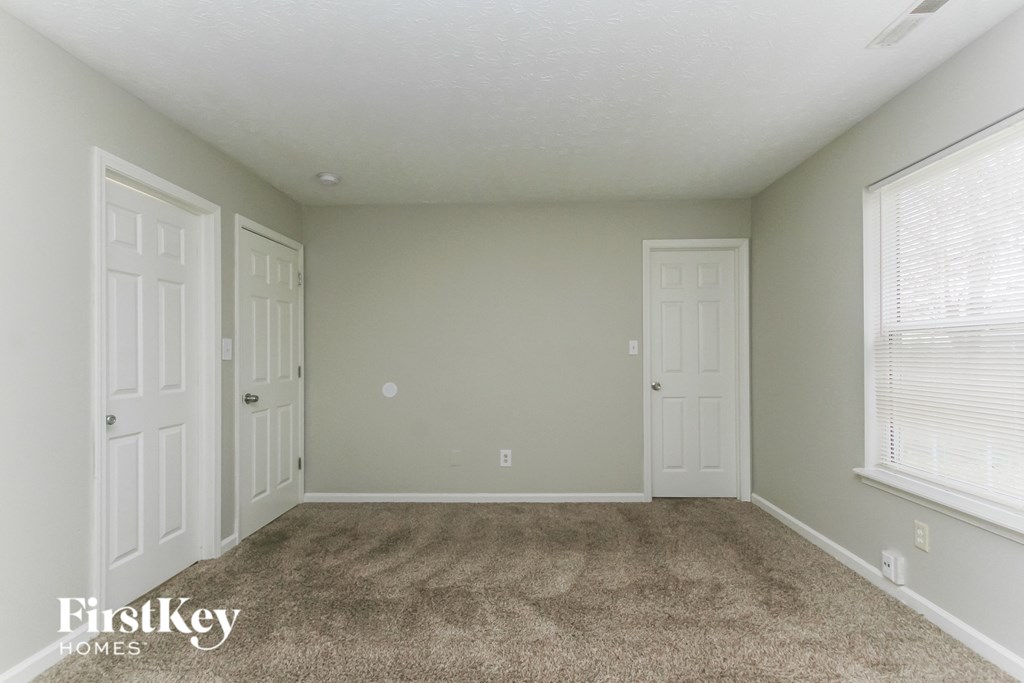 A room with a carpeted floor and three doors.