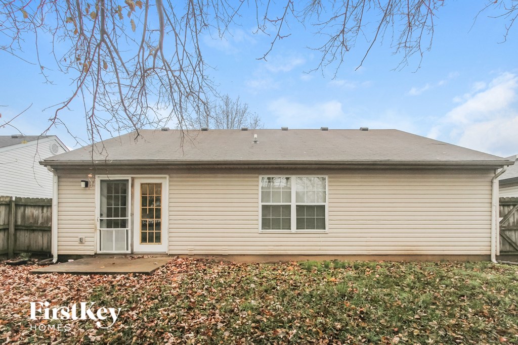 A house with a brown roof and a white door is surrounded by fallen leaves.