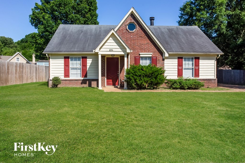 a small white house with red shutters and a lawn