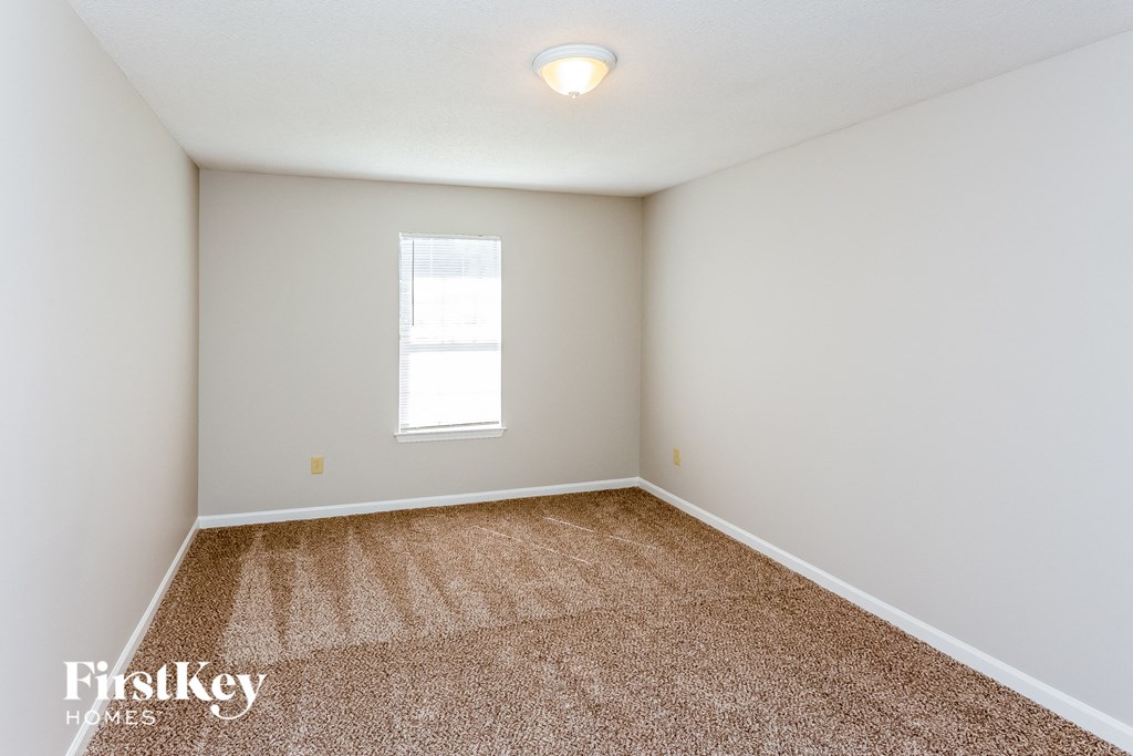 a spacious room with carpet and a window