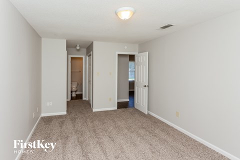 a spacious living room with carpet and a door to the bathroom