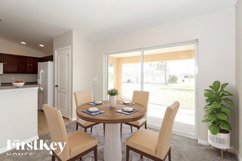 A dining room with a table set for four and a view of the backyard.