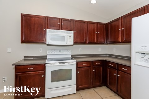 A kitchen with brown cabinets and white appliances.