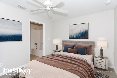 A bedroom with a bed, two lamps, and a painting on the wall.