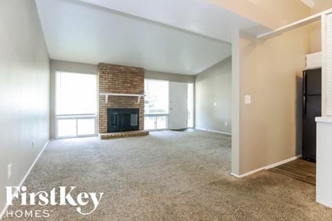 A spacious living room with a fireplace and a large window.