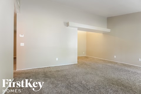 A spacious room with a carpeted floor and a white wall.