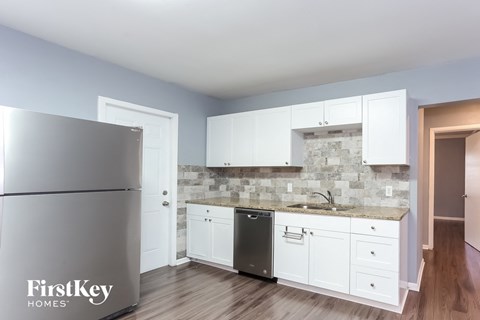 a kitchen with white cabinets and a sink and a refrigerator
