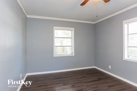 a bedroom with grey walls and wood floors and a ceiling fan