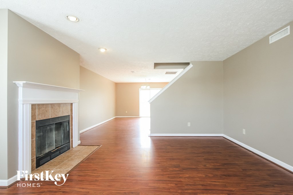 A spacious room with a fireplace and wooden floors.
