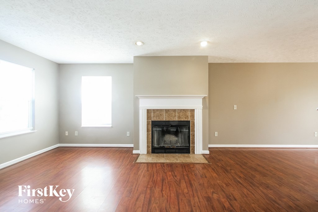 A spacious living room with a fireplace and wooden floors.