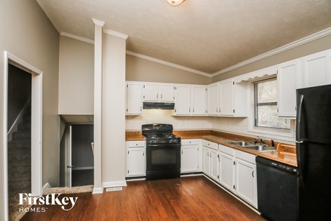A kitchen with a black stove top oven and white cabinets.