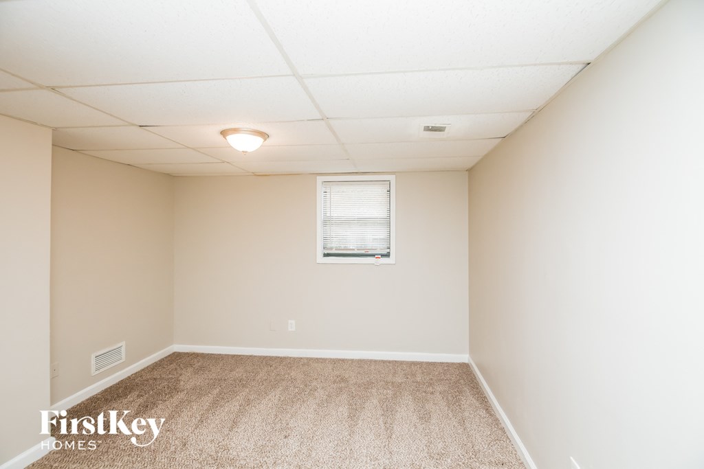 A room with a carpeted floor and a window with blinds.
