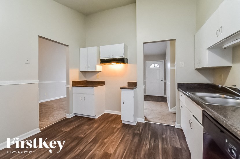 A kitchen with white cabinets and a wooden floor.