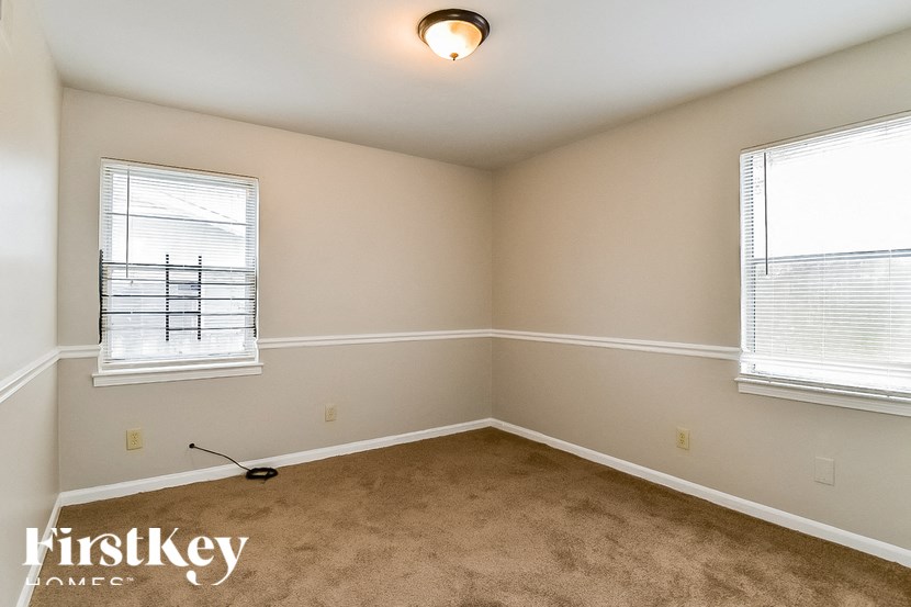 A room with a carpeted floor and two windows.