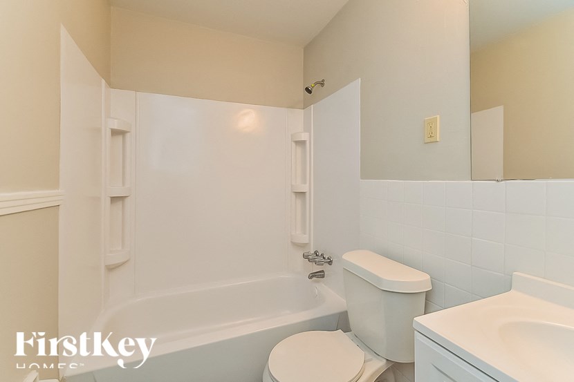 A white toilet sits next to a bathtub in a bathroom.