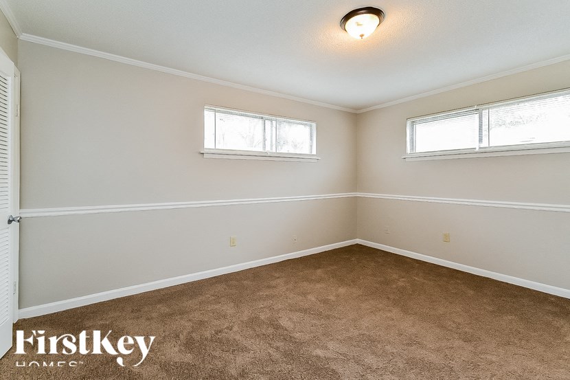 A room with a carpeted floor and two windows.