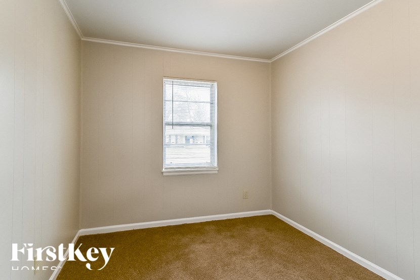 A room with a carpeted floor and a window with blinds.