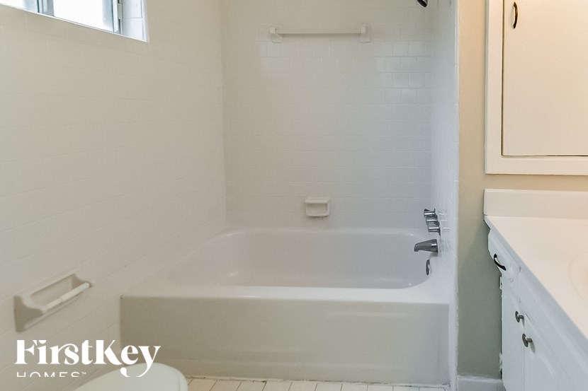 A white bathroom with a tub and a window.