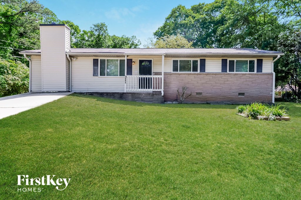 a white and brick house with a lawn in front