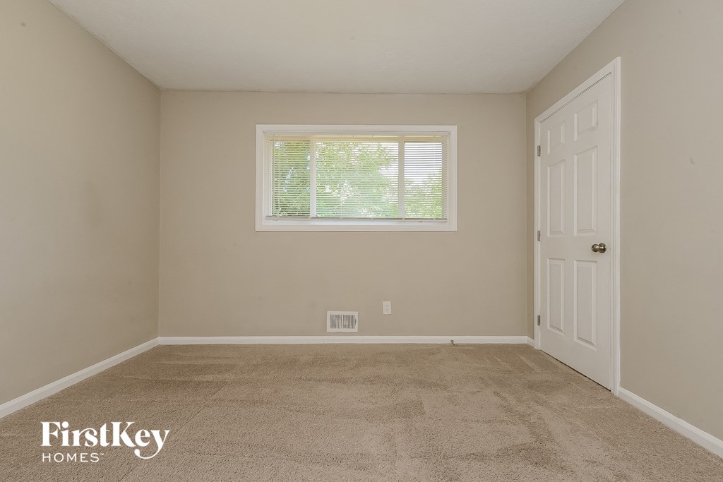 a room with carpet and a window and a white door