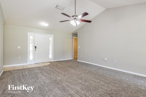 the spacious living room with ceiling fan and carpet