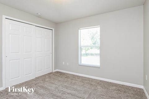 a bedroom with a white door and a window and carpet
