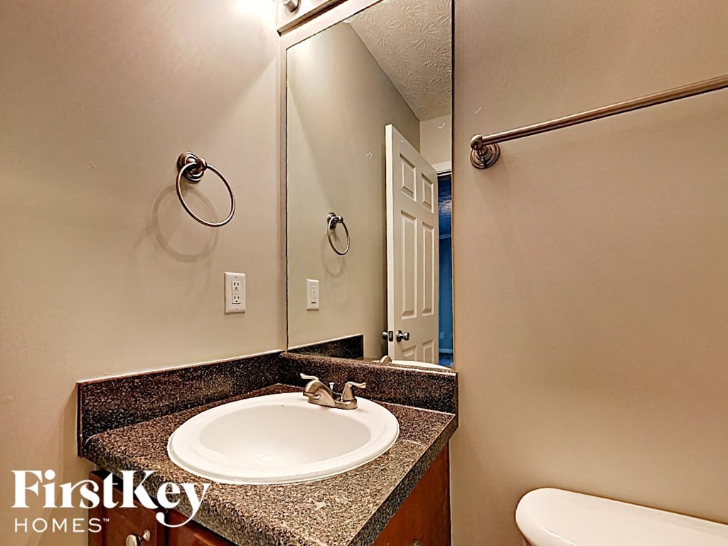 A bathroom with a sink, mirror, and a towel rack.