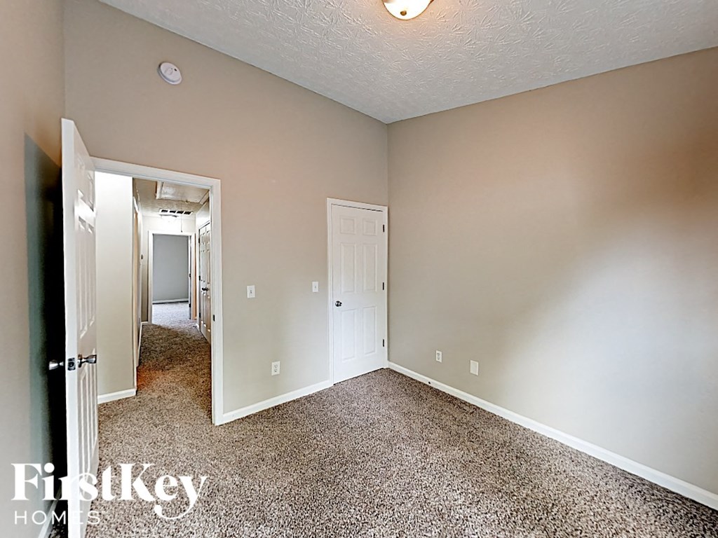 A room with a carpet floor and a door on the right side.