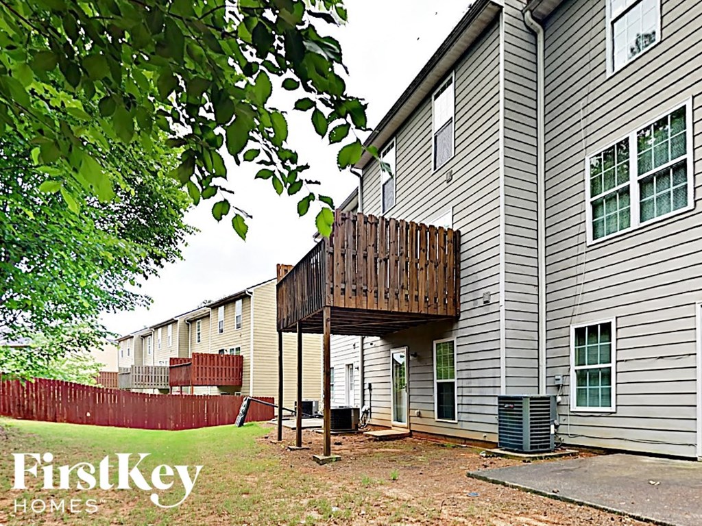 A FirstKey Homes sign is on a tree in front of apartment buildings.