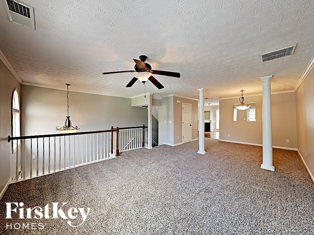 A spacious room with a ceiling fan and a carpeted floor.