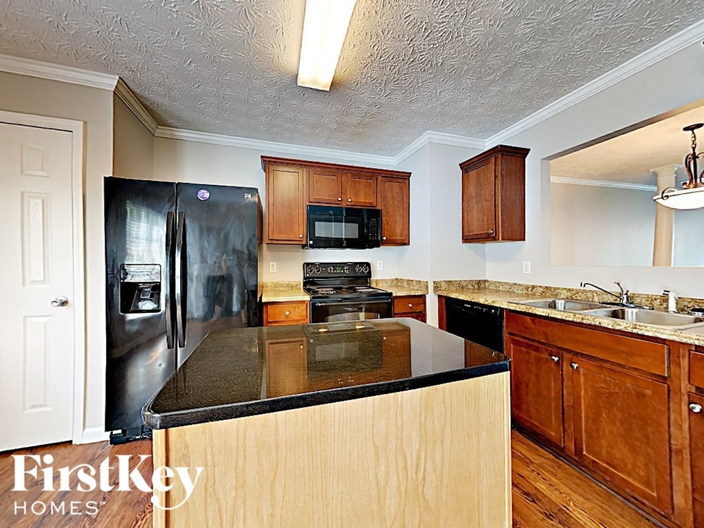 A kitchen with wooden cabinets and a black counter top.
