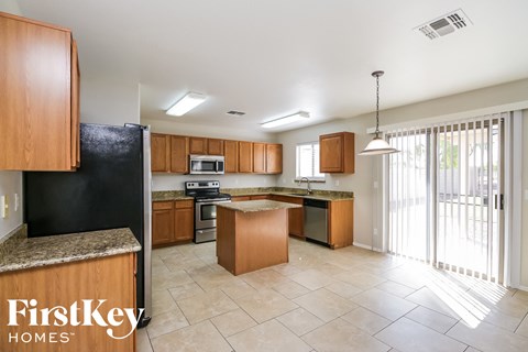 A kitchen with wooden cabinets and a black fridge is shown.