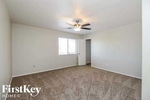 A spacious room with a carpeted floor and a ceiling fan.