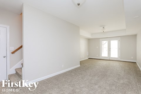 A spacious room with a carpeted floor and a door on the left side.