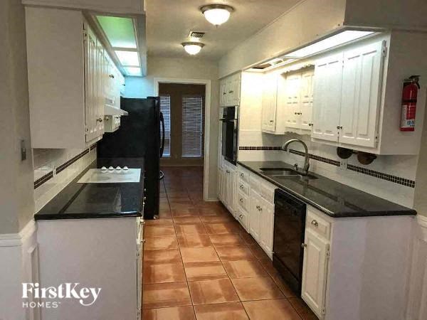 A kitchen with black appliances and white cabinets.