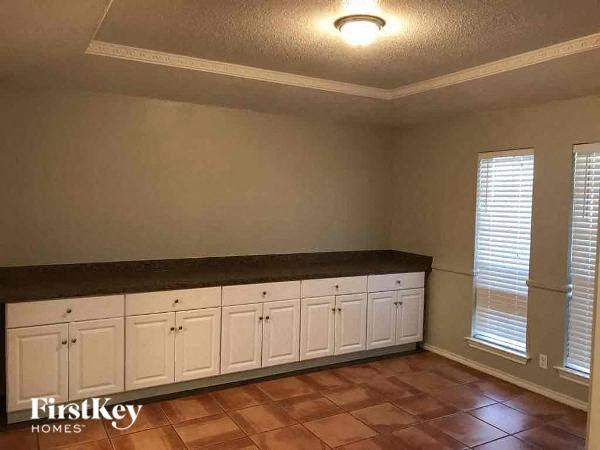 A kitchen with white cabinets and a brown countertop.