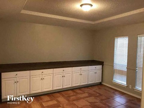 A kitchen with white cabinets and a brown countertop.