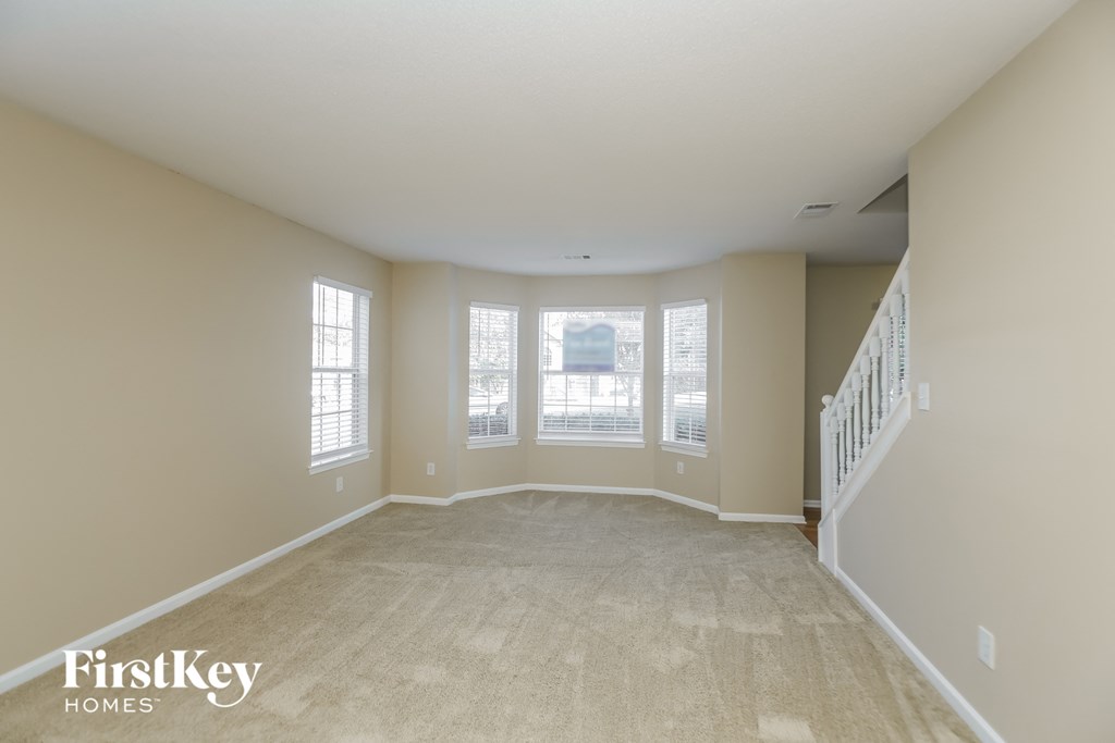 an empty living room with windows and a staircase