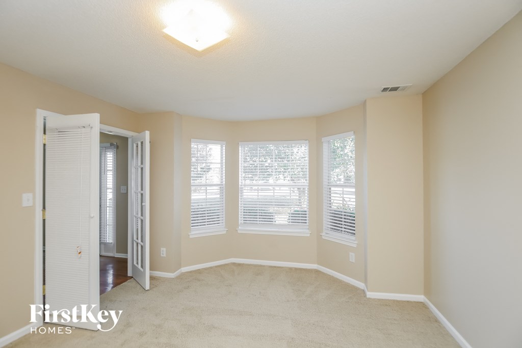 an empty living room with four windows and a closet