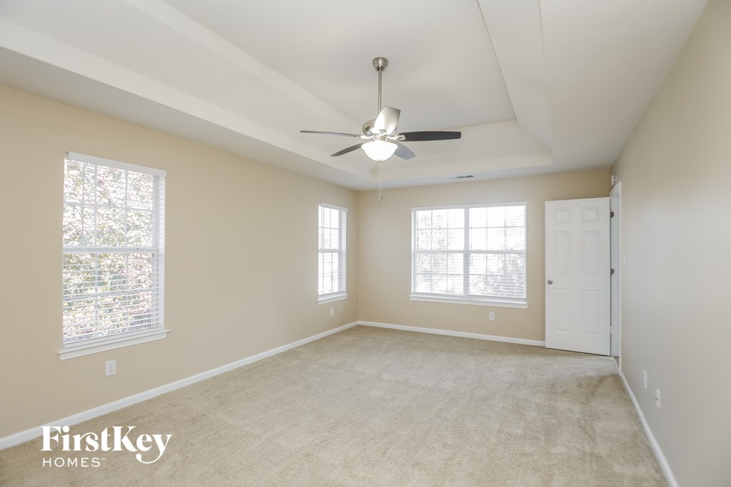 an empty living room with a ceiling fan and two windows