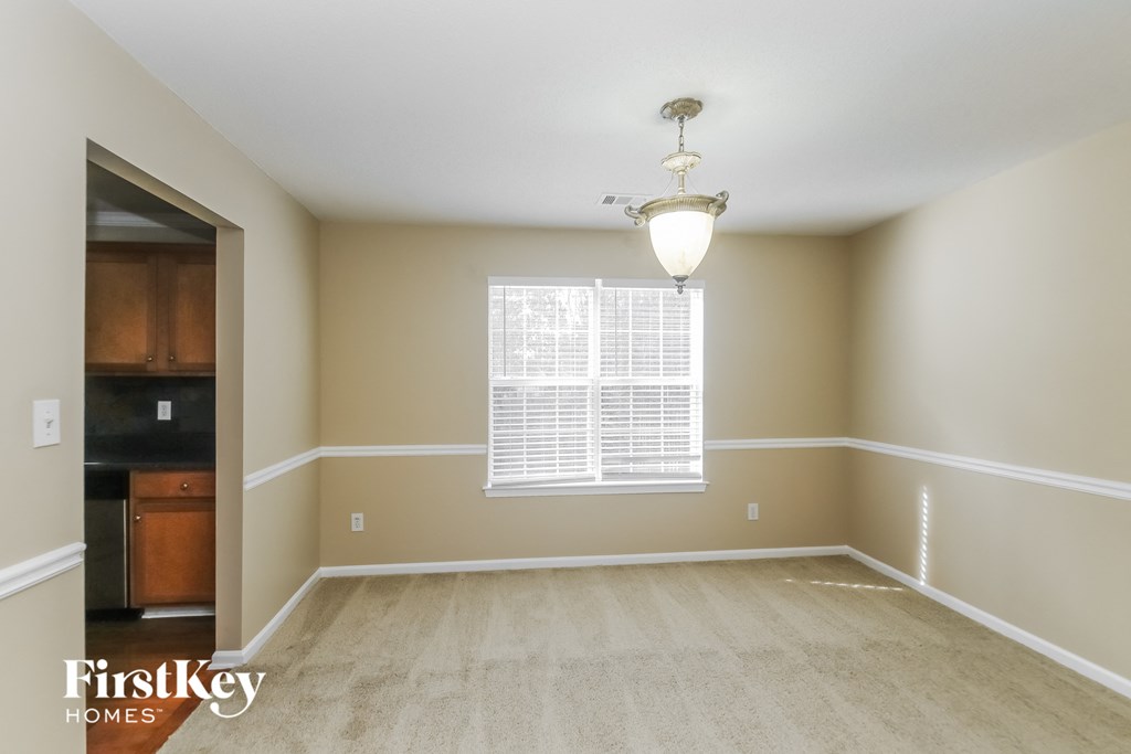 an empty dining room with a window and a light fixture